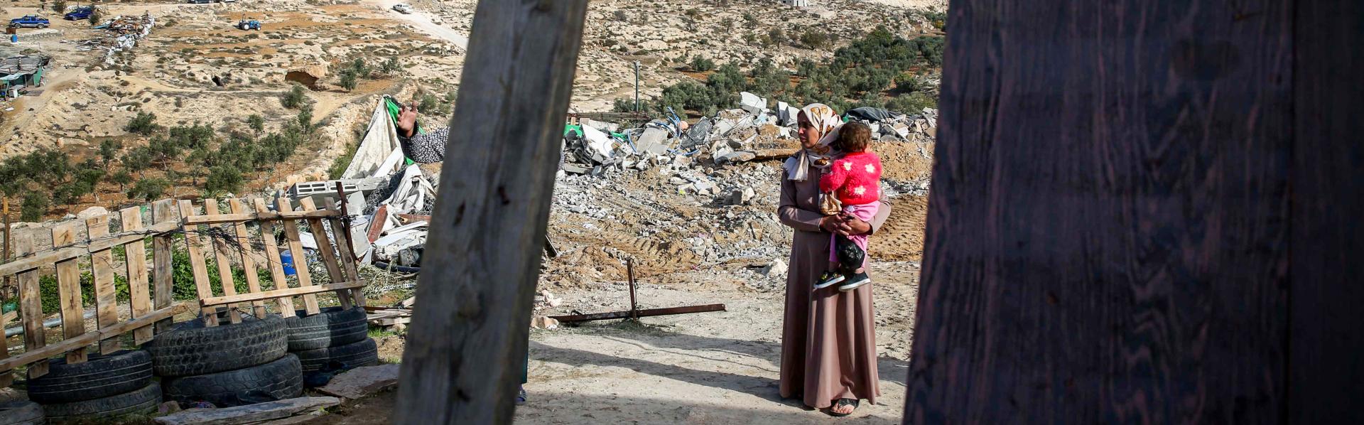 Palestijnse vrouw met baby bij haar afgebroken huis