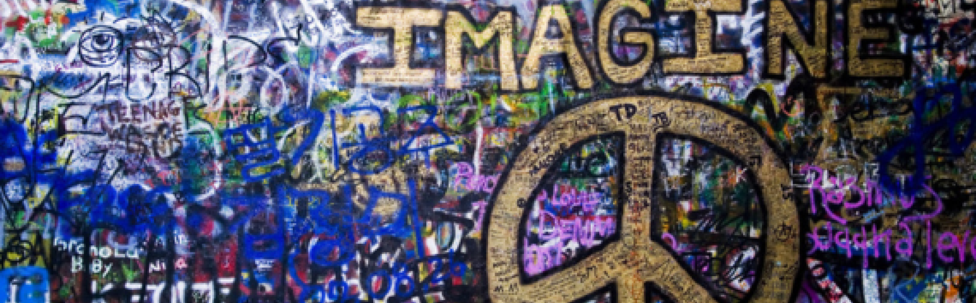 muur volgeklad met graffiti met vredesteken en het woord IMAGINE in goud geschilderd