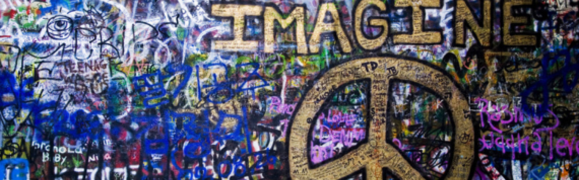 muur vol graffiti en woord IMAGINE en peaceteken in goudverf