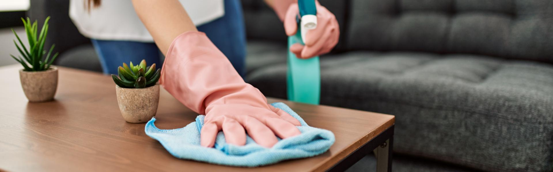 Een housekeeper maakt een salontafeltje schoon.