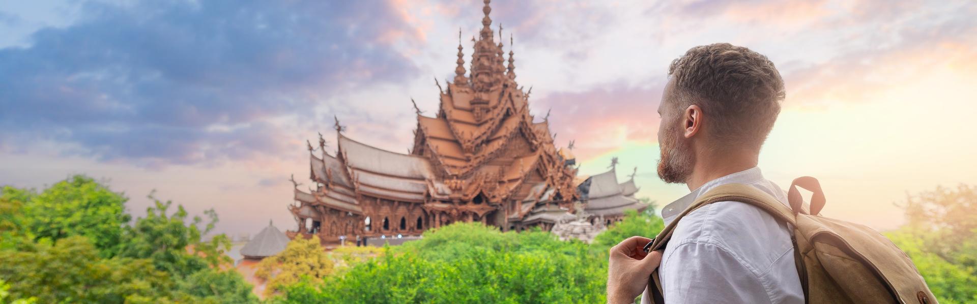 Man met rugzak kijkt naar tempel in de verte tegen vredige avondlucht (pastelkleuren roos en blauw)
