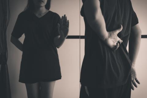 Vrouw toont handstop aan leugenachtige man met hand die vingers kruist achter rug