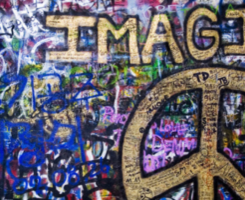 muur vol graffiti en woord IMAGINE en peaceteken in goudverf