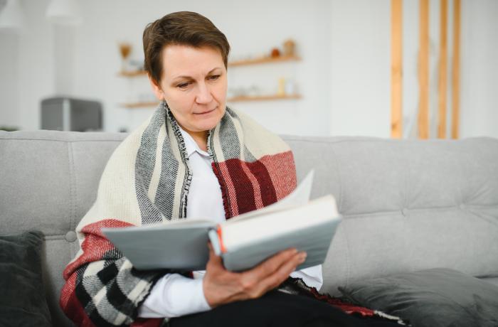 Vijftiger, zestiger leest een boek op de sofa