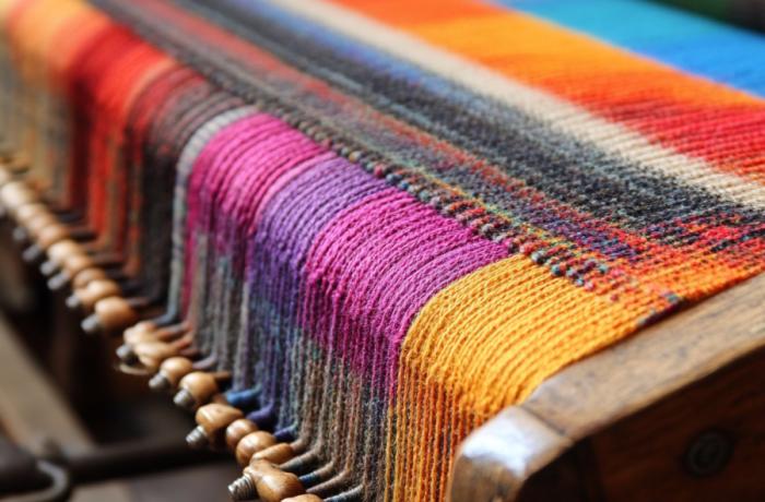 Een lap stof van veelkleurige draden op het weefgetouw